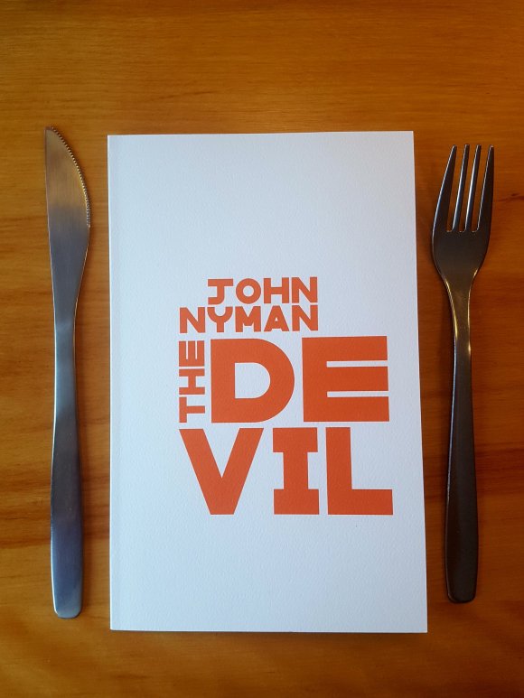 John Nyman's chapbook The Devil, placed on a table with a knife and a fork on either side