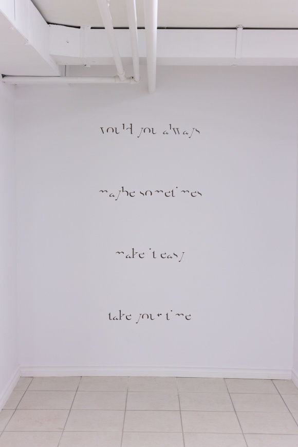 Installation photo of Two Weeks, by John Nyman. The image shows a white gallery wall with text that reads "would you always / maybe sometimes / make it easy / take your time" in a difficult-to-read font.